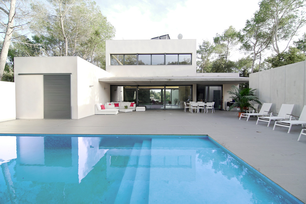 Inspiration pour une façade de maison blanche minimaliste en stuc de taille moyenne et à un étage avec un toit plat.