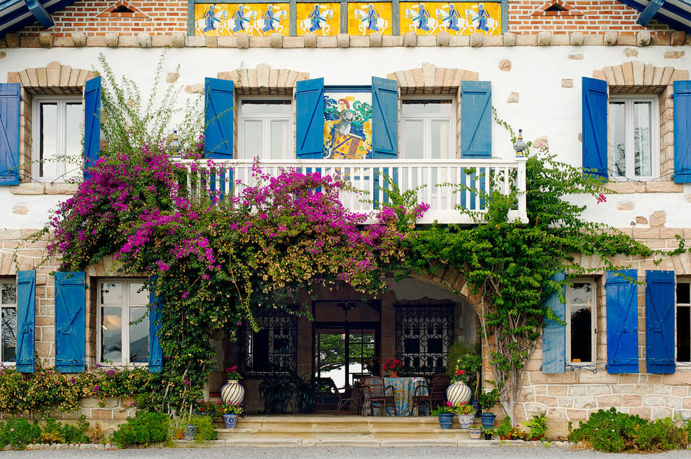 Imagen de fachada mediterránea grande de tres plantas con revestimientos combinados