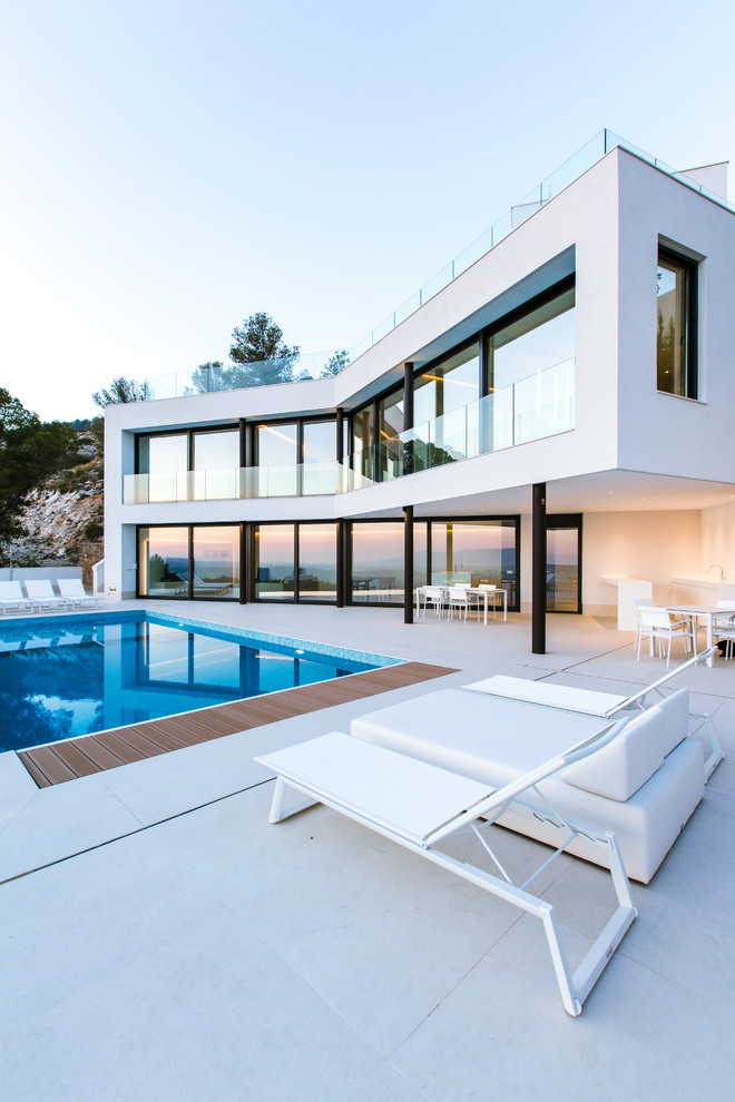 Réalisation d'une grande façade de maison blanche minimaliste à un étage avec un toit plat.
