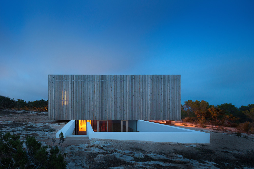 Imagen de fachada de casa gris mediterránea de tamaño medio de dos plantas con revestimiento de madera, tejado plano y tejado de varios materiales