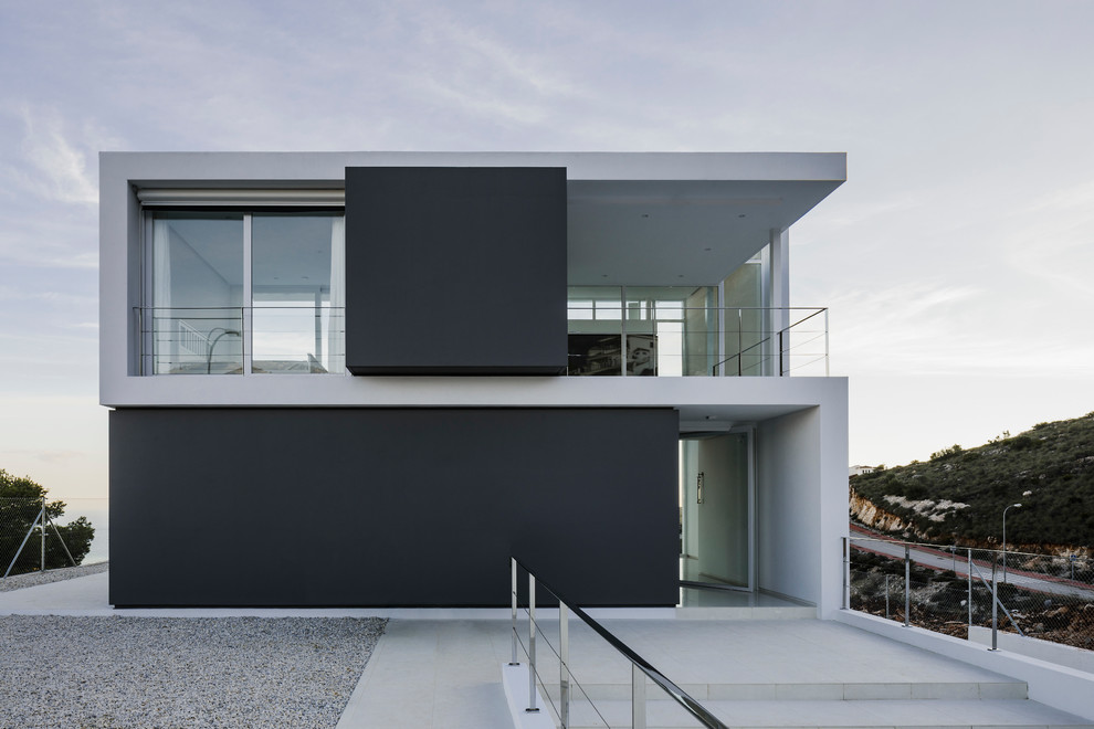Imagen de fachada de casa blanca moderna grande de dos plantas con revestimiento de aglomerado de cemento, tejado plano y tejado de varios materiales