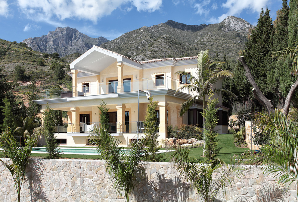 Diseño de fachada beige mediterránea grande de dos plantas con revestimiento de estuco y tejado a dos aguas