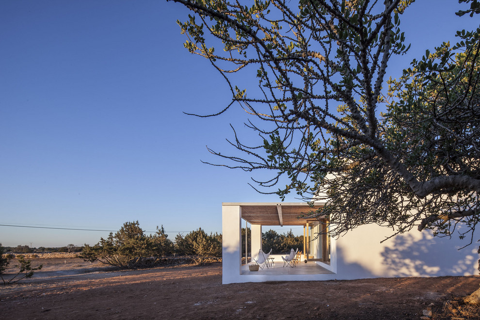 Cette photo montre une petite façade de maison blanche méditerranéenne de plain-pied avec un revêtement mixte, un toit plat et un toit mixte.
