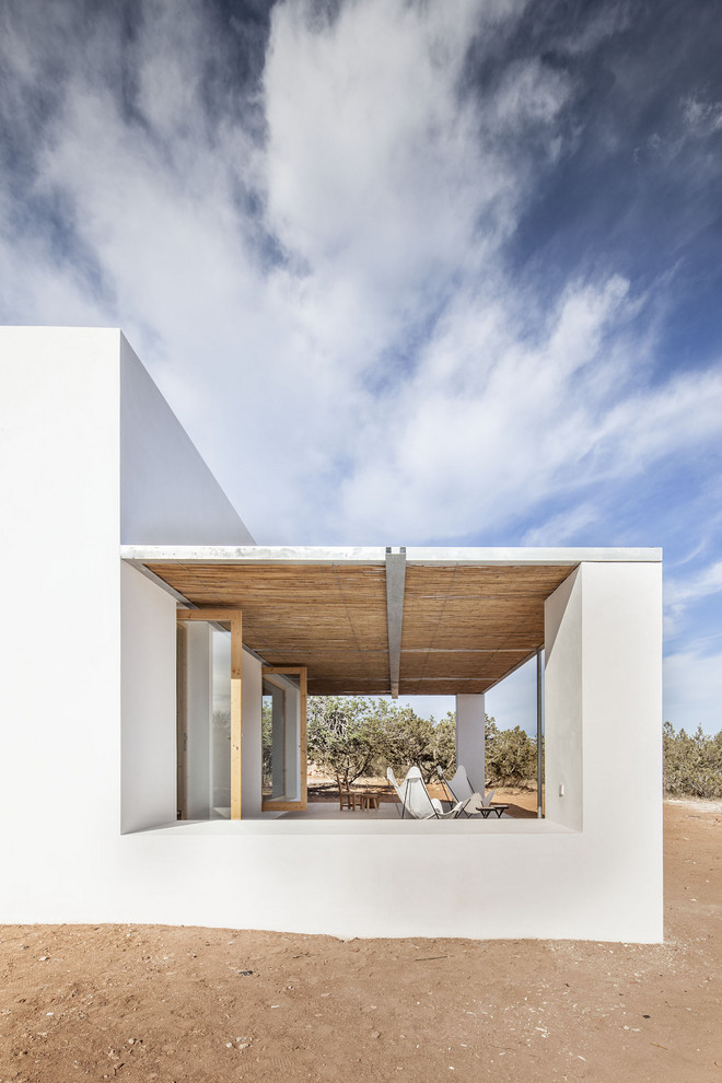 Imagen de fachada de casa blanca mediterránea pequeña de una planta con revestimientos combinados, tejado plano y tejado de varios materiales