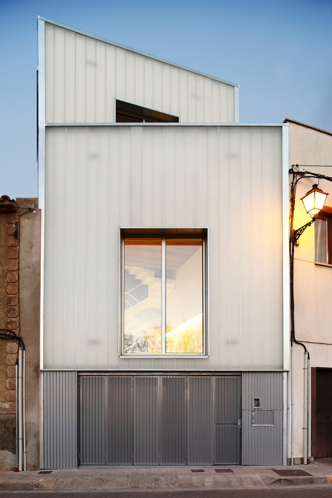 Foto på ett mellanstort industriellt grått hus i flera nivåer, med pulpettak och blandad fasad