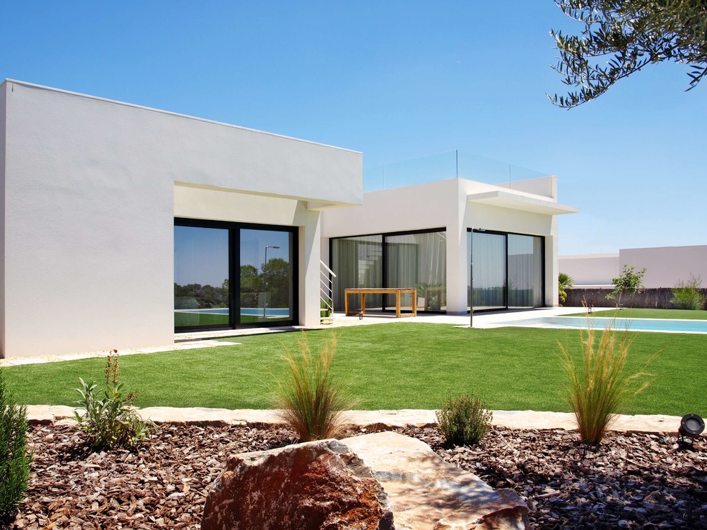 Imagen de fachada de casa blanca minimalista con revestimiento de piedra y tejado plano