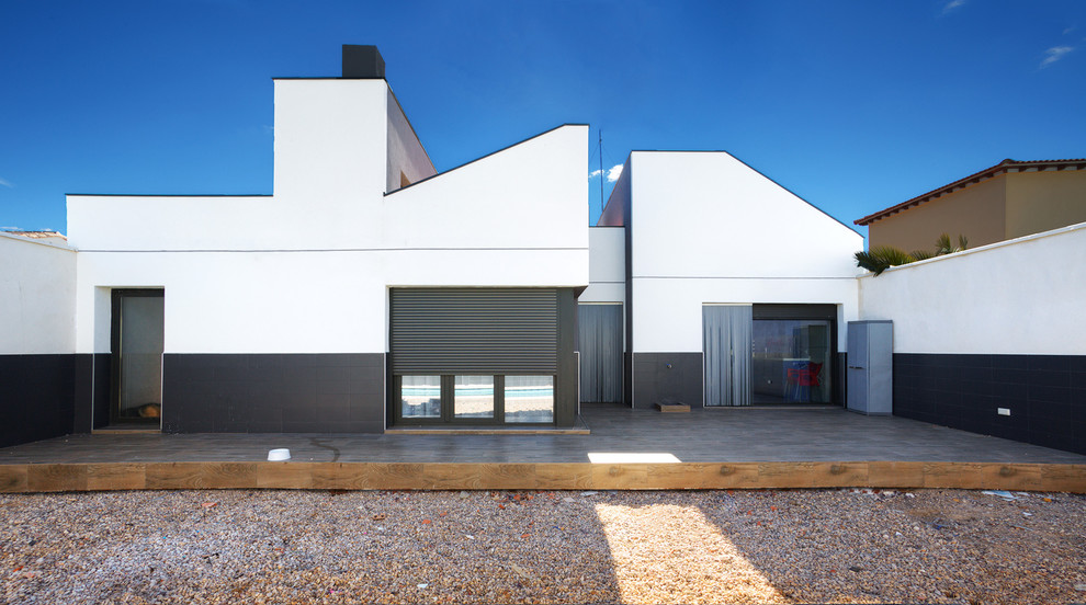 Diseño de fachada de casa blanca moderna de tamaño medio de una planta con revestimiento de estuco, tejado de un solo tendido y tejado de teja de barro