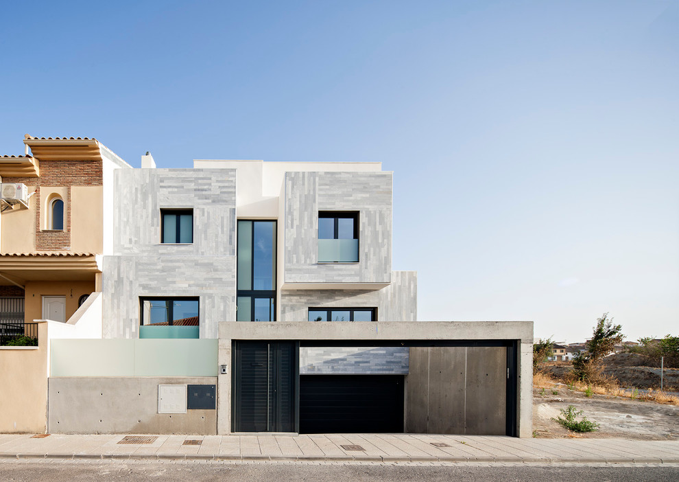 Großes, Dreistöckiges Modernes Haus mit Steinfassade, grauer Fassadenfarbe und Flachdach in Sonstige
