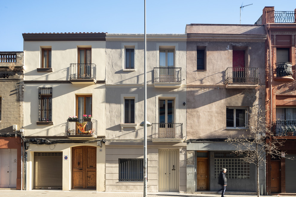 Cette image montre une grande façade de maison de ville beige méditerranéenne à deux étages et plus avec un revêtement mixte, un toit en tuile et un toit plat.