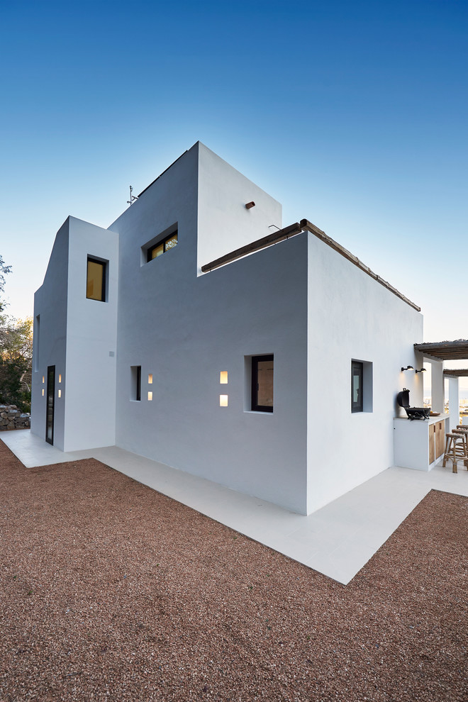 Modelo de fachada blanca mediterránea grande de tres plantas con revestimiento de estuco y tejado plano