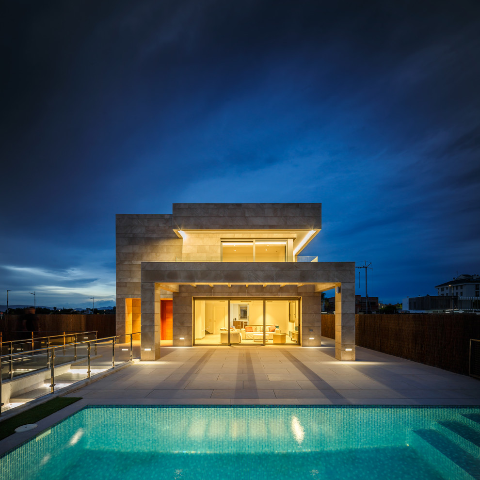Cette image montre une façade de maison beige minimaliste de taille moyenne et à un étage avec un toit plat.