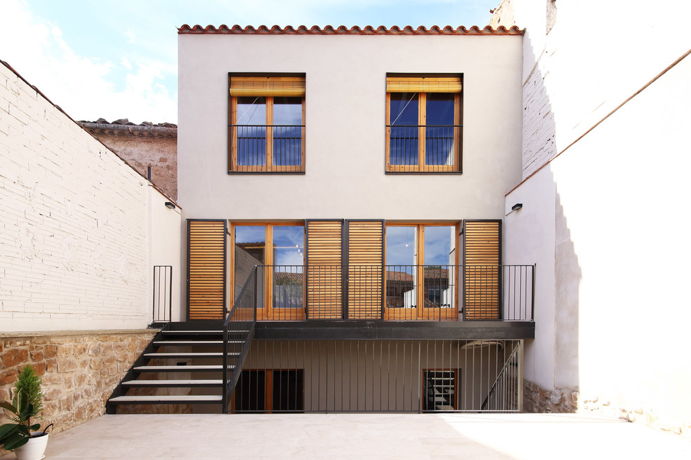This is an example of a white mediterranean house exterior in Barcelona with three floors and a flat roof.