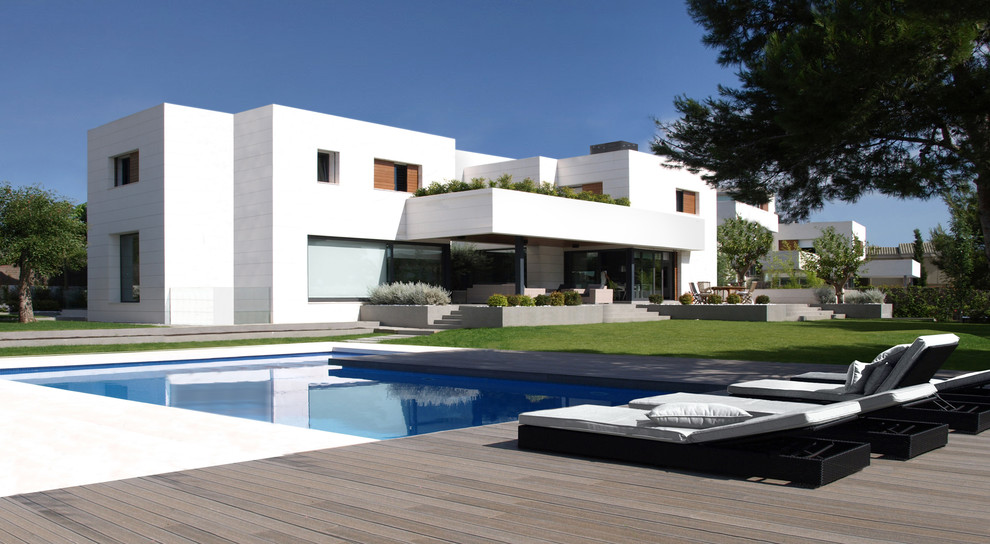 Large trendy white two-story stone flat roof photo in Valencia