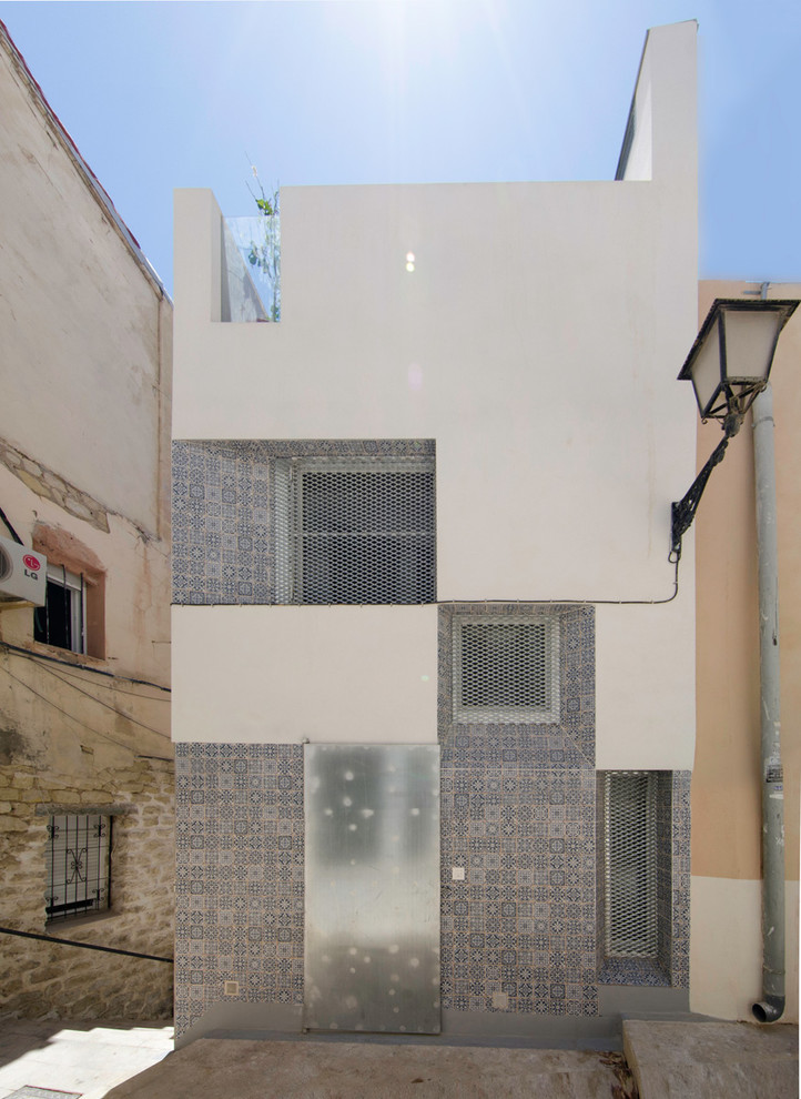 Diseño de fachada blanca mediterránea de tamaño medio de tres plantas con revestimiento de hormigón y tejado plano