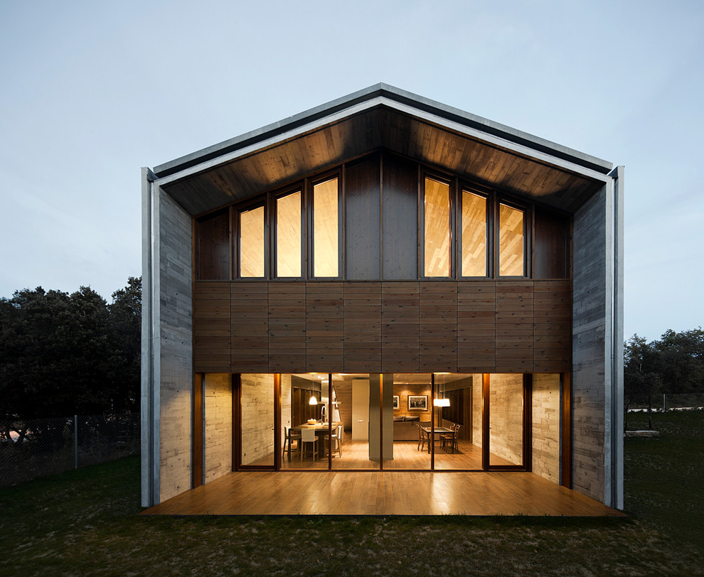 Cette photo montre une grande façade de maison grise tendance en béton à un étage avec un toit à deux pans.