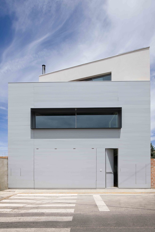 Cette image montre une façade de maison grise design de taille moyenne et à deux étages et plus avec un revêtement mixte et un toit plat.