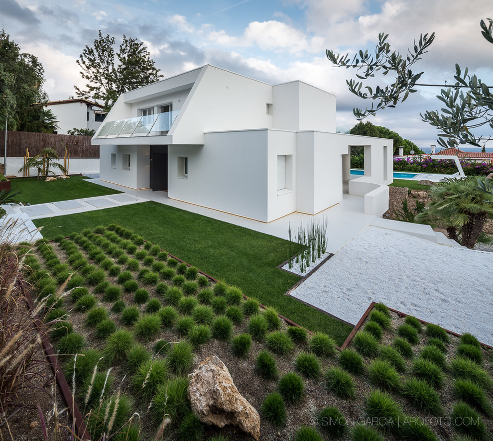 На фото: двухэтажный, белый дом среднего размера в средиземноморском стиле с облицовкой из цементной штукатурки и плоской крышей с