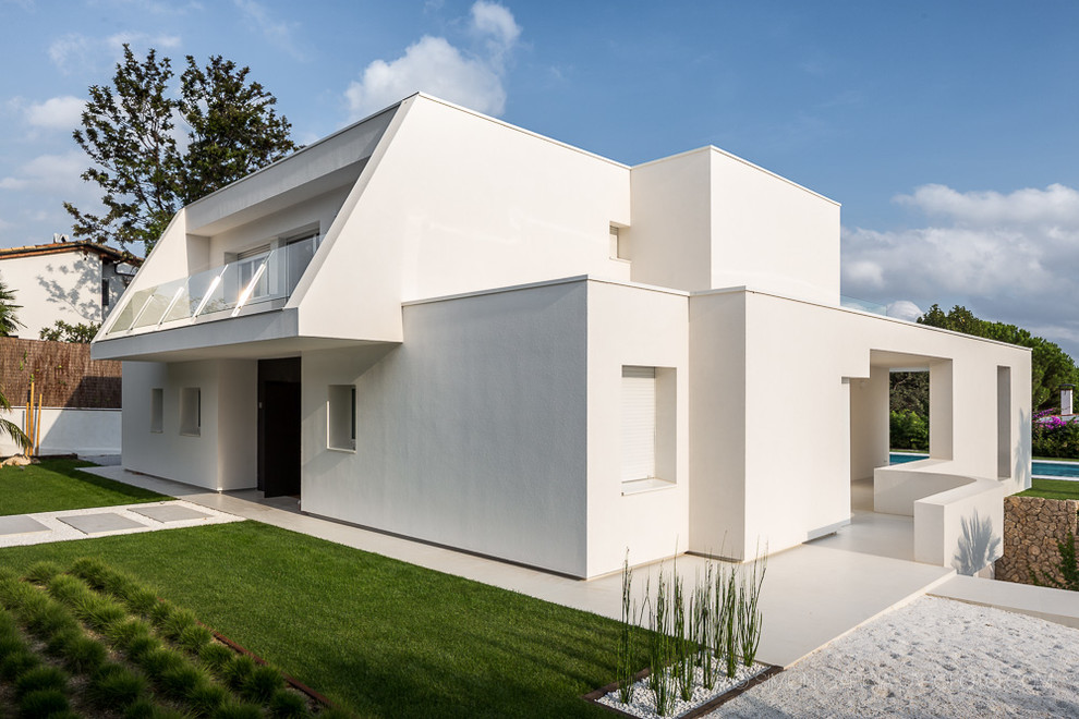 Cette image montre une façade de maison blanche design en panneau de béton fibré de taille moyenne et à un étage avec un toit plat.