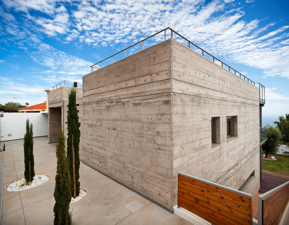 Стильный дизайн: серый дом среднего размера в современном стиле с разными уровнями, облицовкой из бетона и плоской крышей - последний тренд
