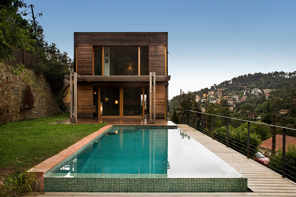 Inspiration for a medium sized and brown contemporary two floor house exterior in Barcelona with wood cladding and a flat roof.