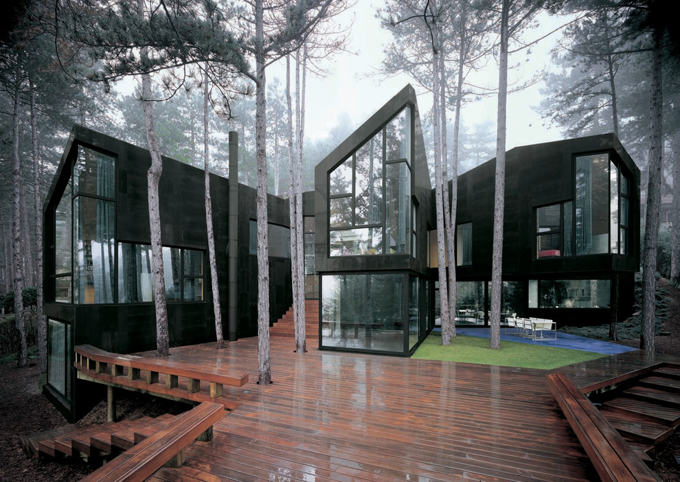 This is an example of a black and expansive contemporary house exterior in Madrid with three floors and stone cladding.