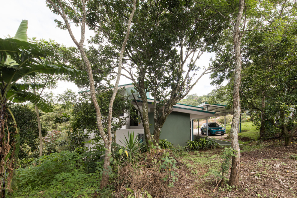 Foto på ett tropiskt grönt hus i flera nivåer, med tak i metall