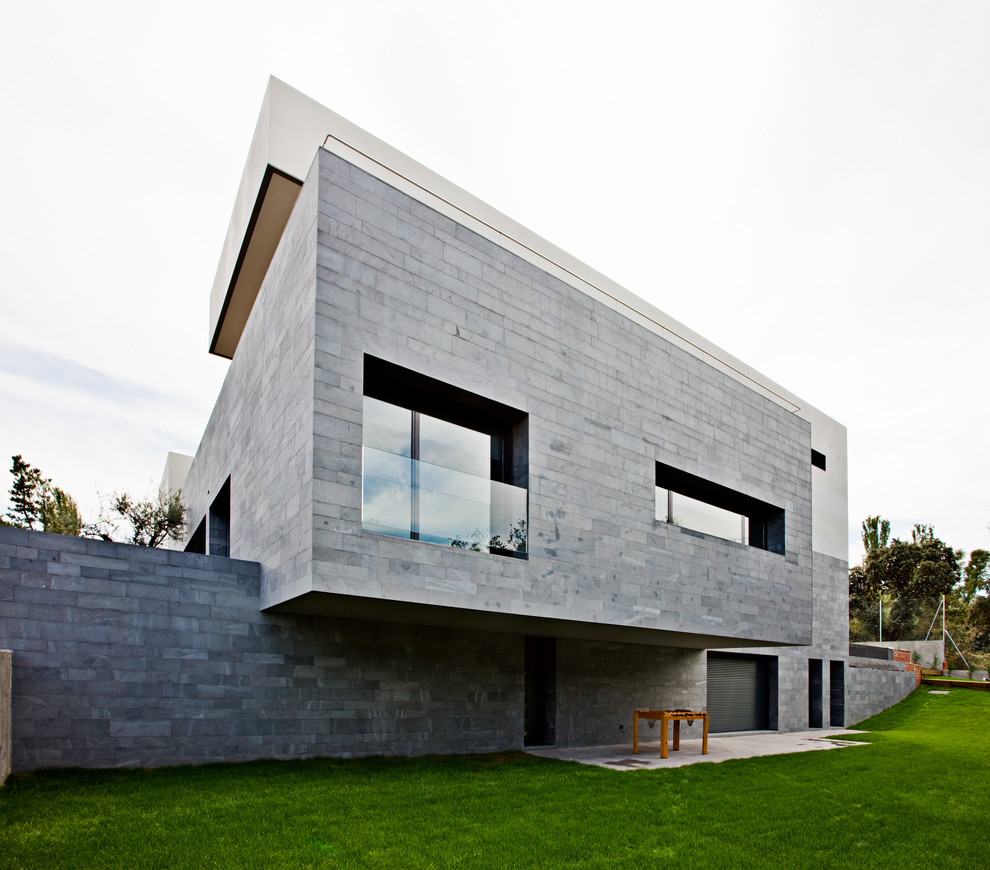 Ejemplo de fachada gris actual grande de tres plantas con revestimiento de piedra y tejado plano