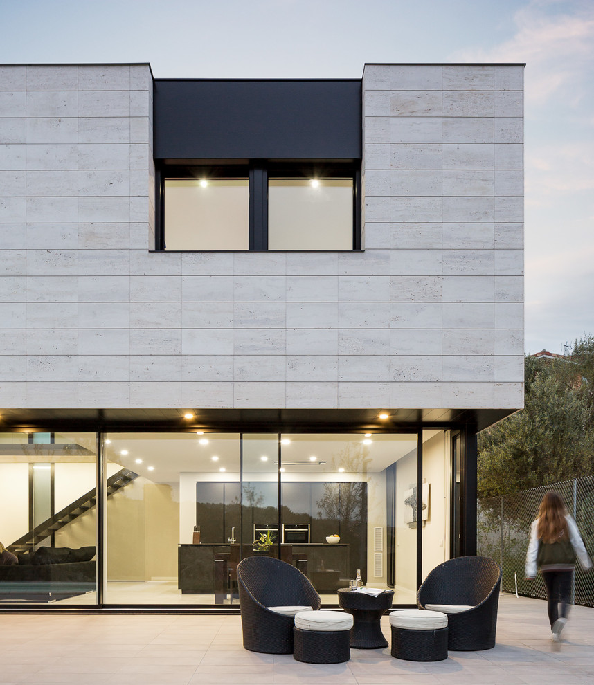 Cette photo montre une façade de maison moderne en pierre de taille moyenne et à un étage avec un toit plat.