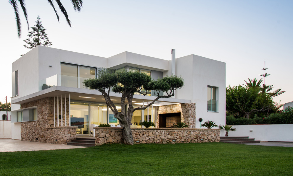 Diseño de fachada blanca mediterránea de tamaño medio de dos plantas con revestimientos combinados y tejado plano
