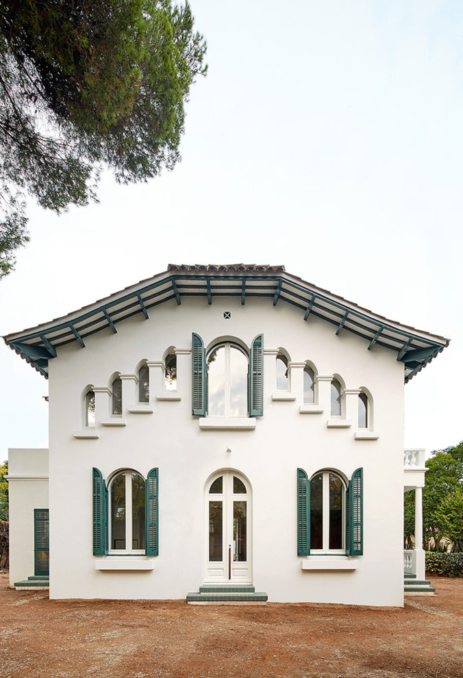 Cette photo montre une façade de maison blanche chic en stuc de taille moyenne et à un étage avec un toit à croupette.