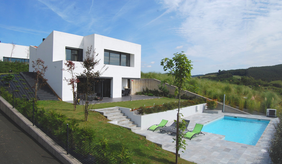 На фото: двухэтажный, белый дом среднего размера в современном стиле с плоской крышей и облицовкой из цементной штукатурки с