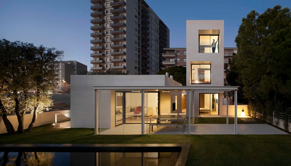 Photo of a medium sized and white contemporary house exterior in Barcelona with three floors, mixed cladding and a flat roof.