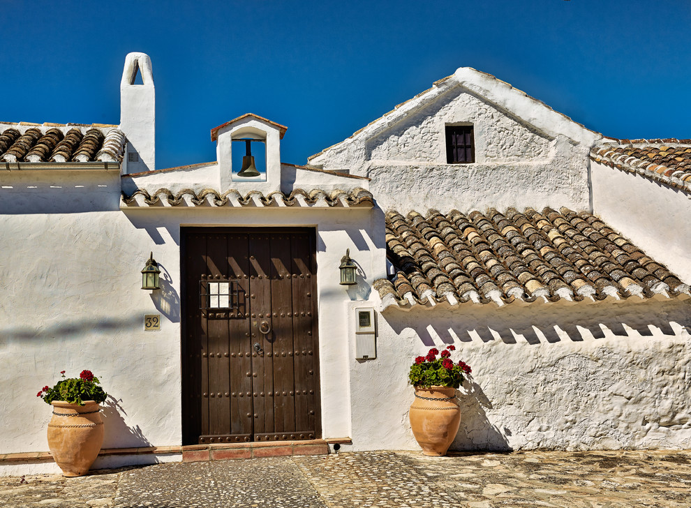 Cette image montre une façade de maison beige méditerranéenne en stuc de plain-pied et de taille moyenne avec un toit à deux pans.