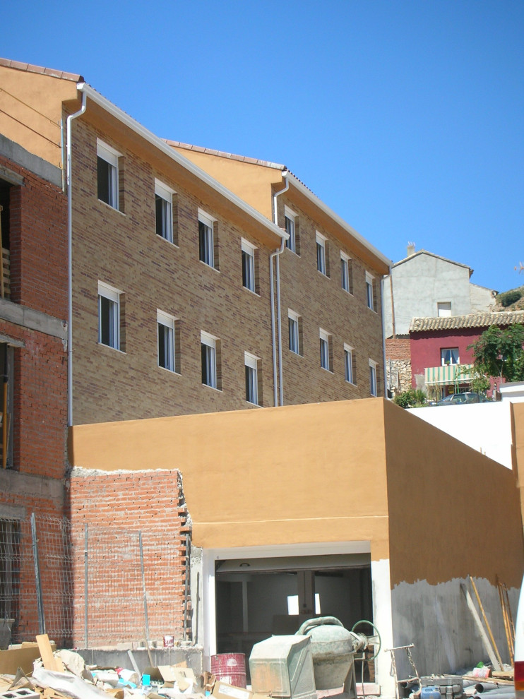 Cette image montre un très grande façade d'immeuble minimaliste en brique avec un toit à deux pans et un toit en tuile.