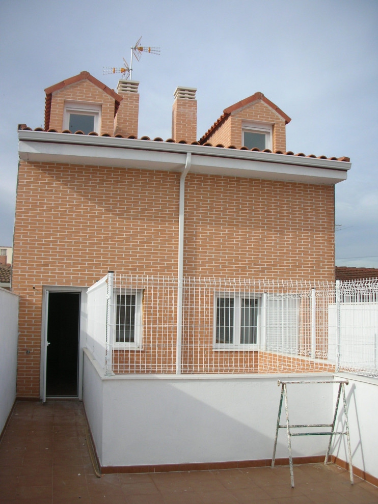 Idée de décoration pour un petite façade d'immeuble minimaliste en brique avec un toit à deux pans et un toit en tuile.