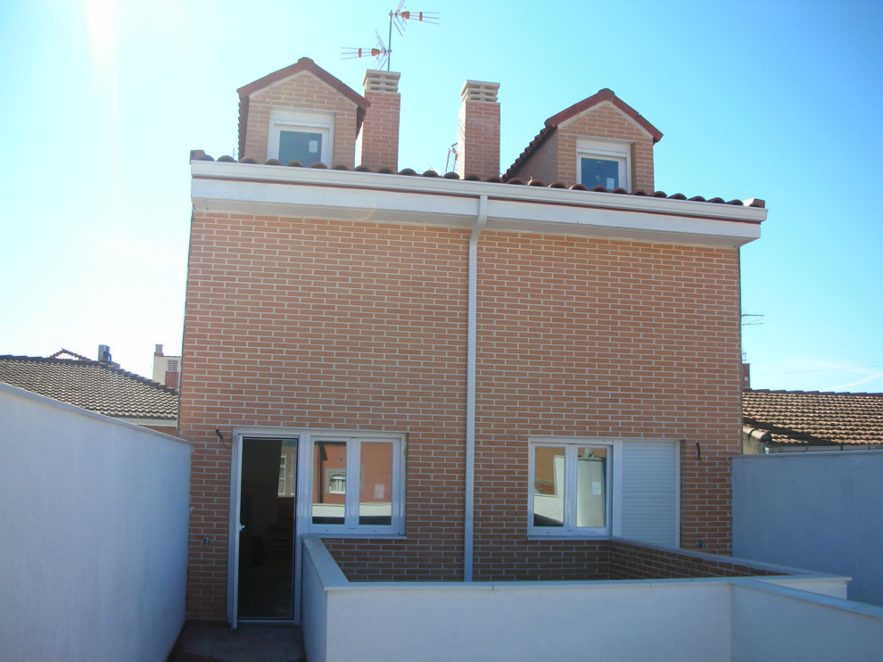 Imagen de fachada de piso roja moderna pequeña de tres plantas con revestimiento de ladrillo, tejado a dos aguas y tejado de teja de barro