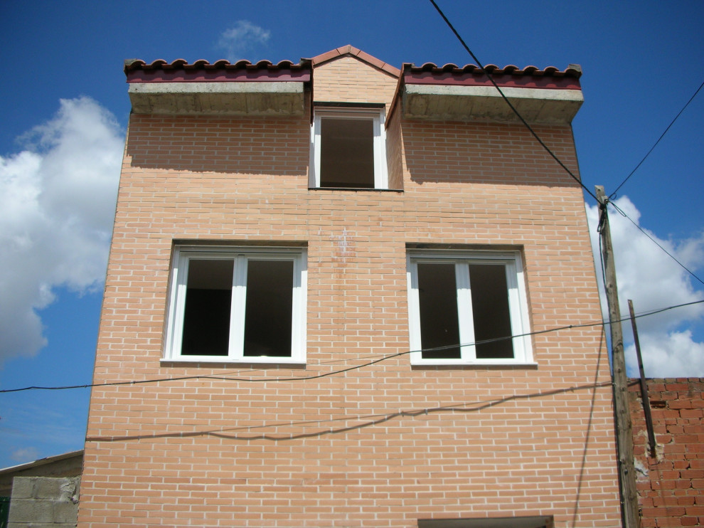 Foto på ett litet funkis rött lägenhet, med tre eller fler plan, tegel, sadeltak och tak med takplattor