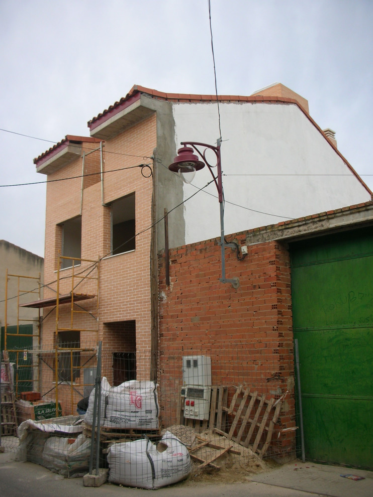 Ispirazione per la facciata di un appartamento piccolo rosso moderno a tre piani con rivestimento in mattoni, tetto a capanna e copertura in tegole