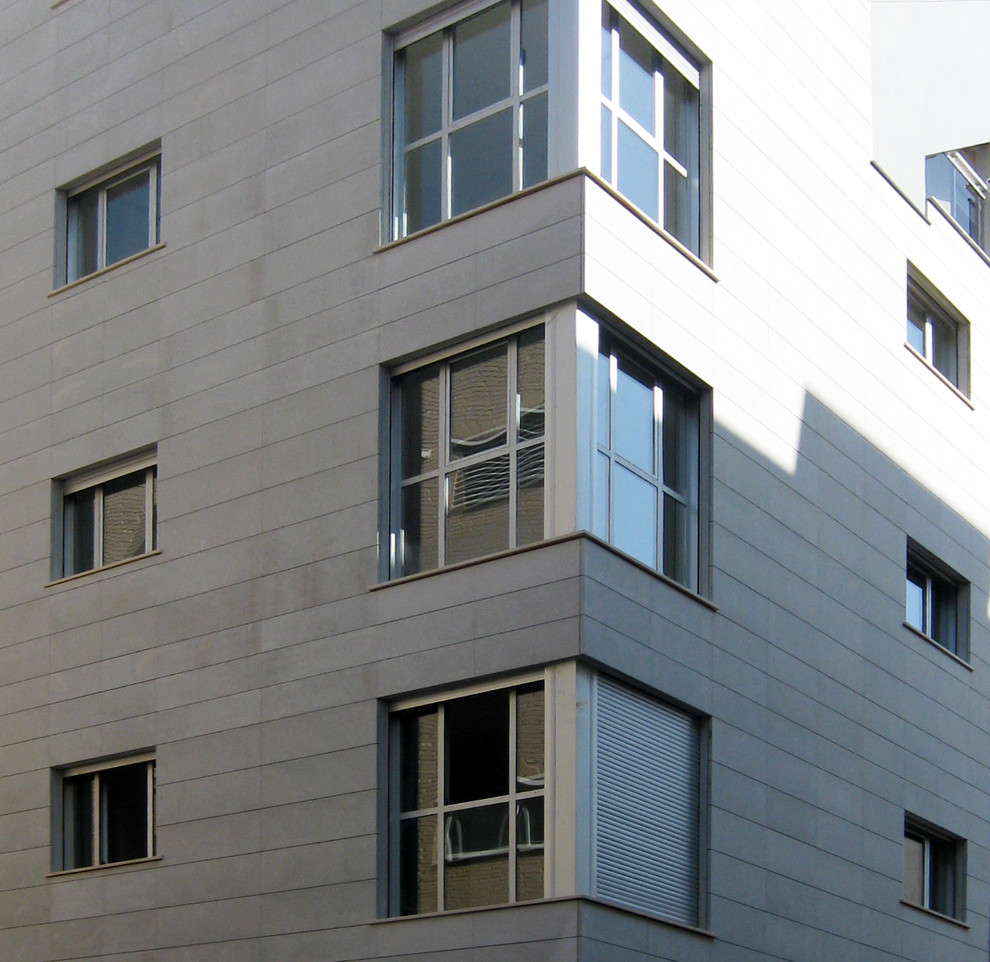 Modelo de fachada gris moderna grande de tres plantas con revestimiento de piedra y tejado plano