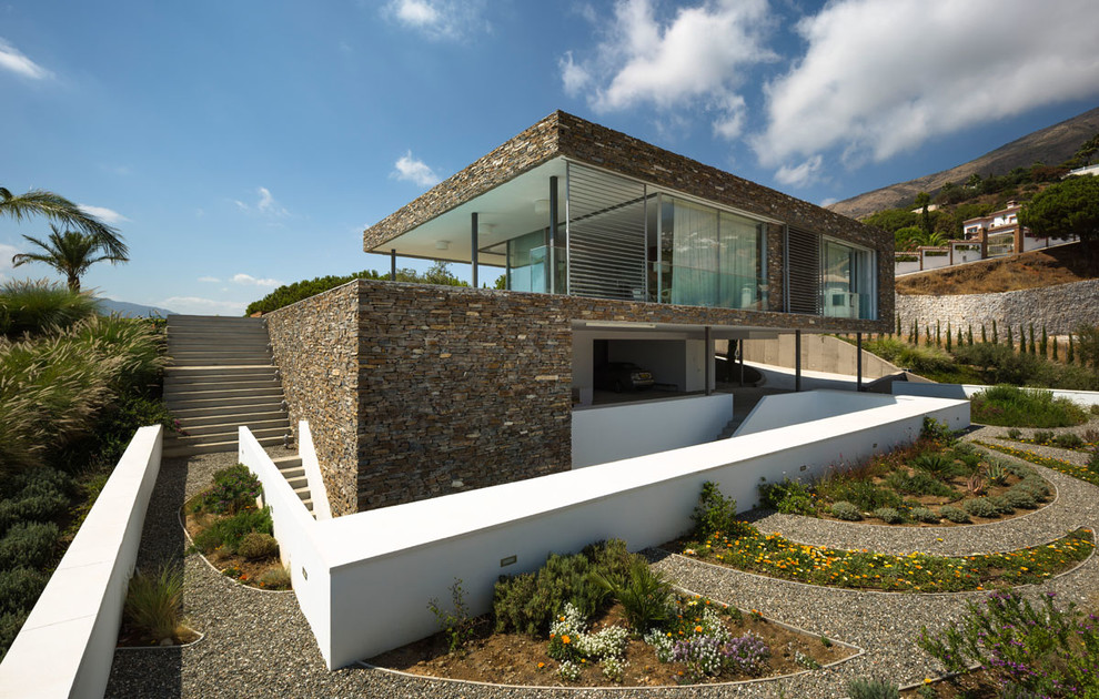 На фото: трехэтажный, коричневый дом среднего размера в современном стиле с облицовкой из камня и плоской крышей с