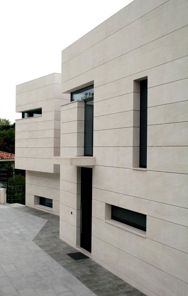 Esempio della villa beige contemporanea a due piani con rivestimento in pietra, tetto piano e copertura mista