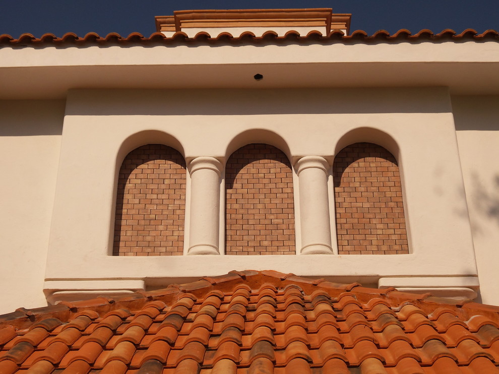 Immagine della facciata di una casa grande bianca mediterranea a tre piani con rivestimenti misti e tetto a padiglione