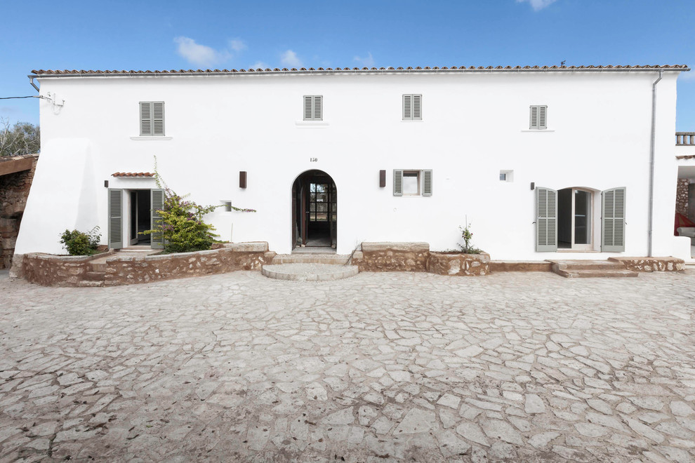 Idée de décoration pour une façade de maison blanche méditerranéenne en stuc à un étage et de taille moyenne avec un toit à deux pans.