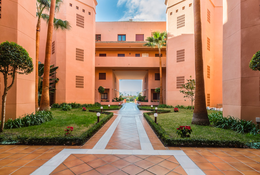 他の地域にある高級な巨大な地中海スタイルのおしゃれな家の外観 (漆喰サイディング、オレンジの外壁、アパート・マンション) の写真