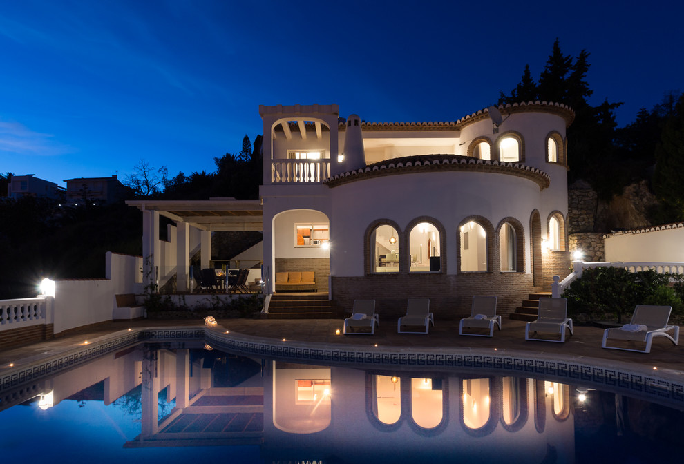 他の地域にある高級な地中海スタイルのおしゃれな家の外観 (レンガサイディング) の写真