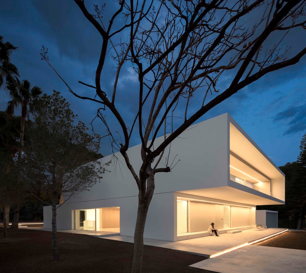 Diseño de fachada blanca mediterránea grande de dos plantas con revestimientos combinados y tejado plano