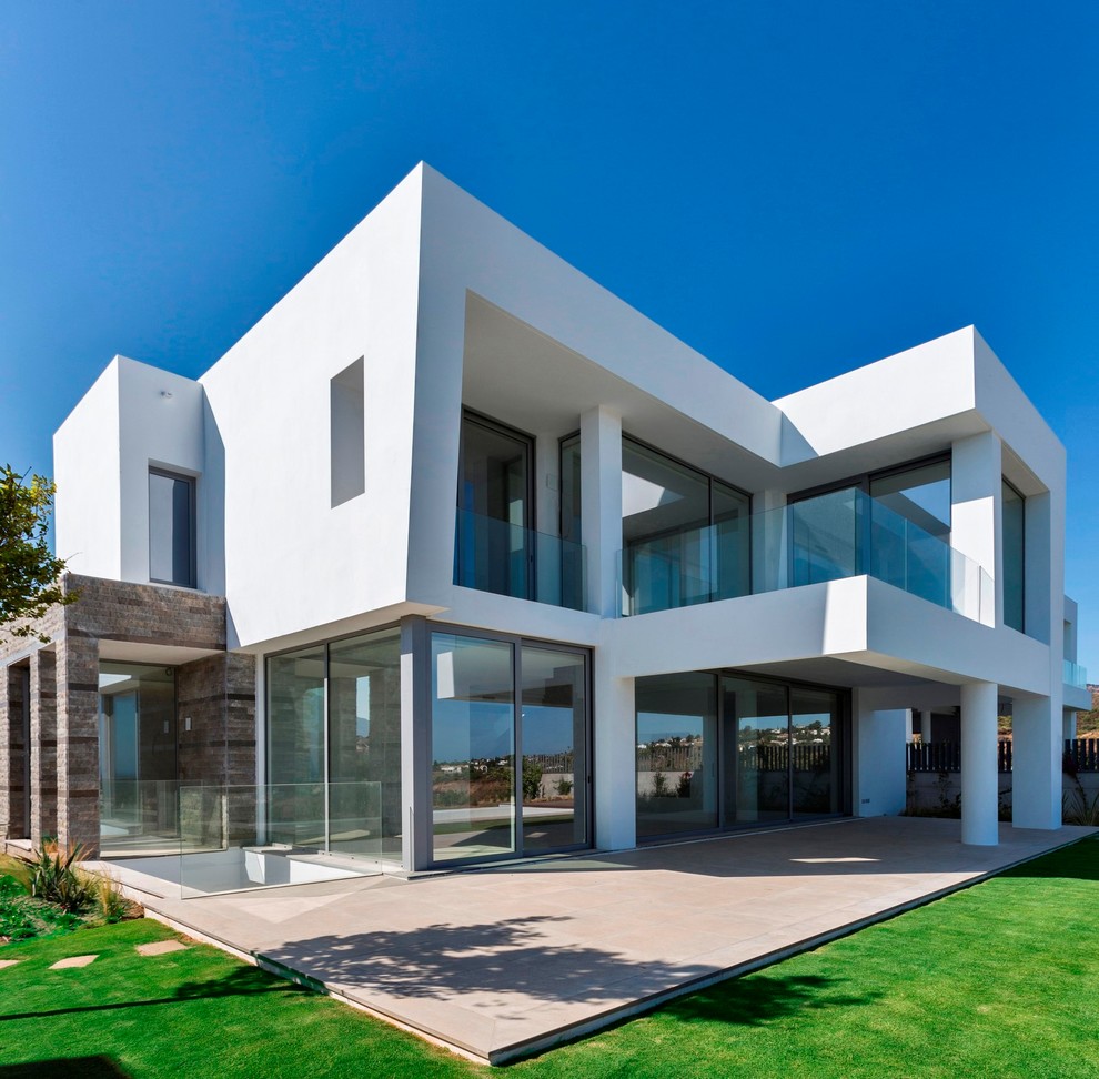 Imagen de fachada de casa blanca actual grande de dos plantas con tejado plano y revestimientos combinados