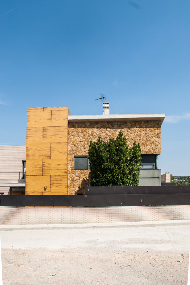 Cette photo montre une grande façade de maison marron tendance en pierre à deux étages et plus avec un toit en appentis et un toit en tuile.