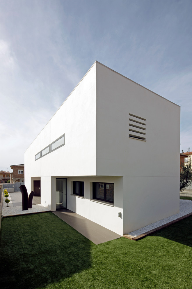 Diseño de fachada de casa blanca actual grande de dos plantas con revestimiento de estuco, tejado plano y tejado de varios materiales