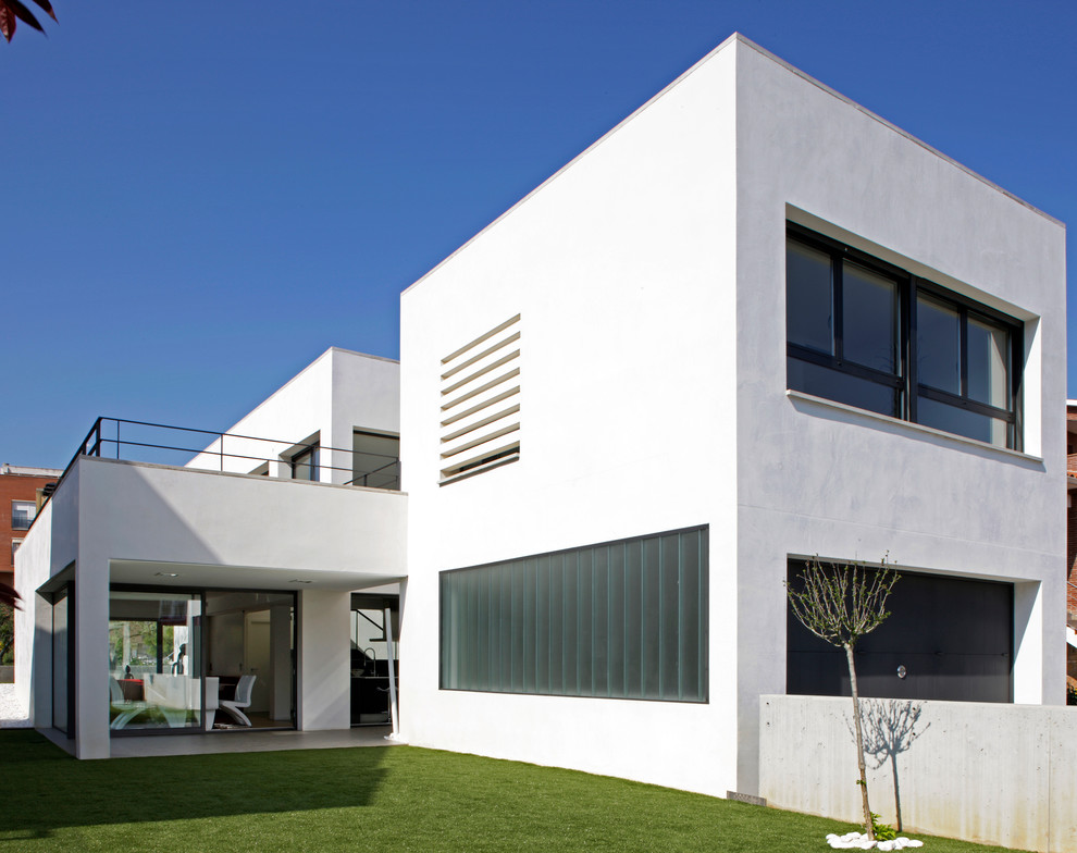 Imagen de fachada de casa blanca actual grande de dos plantas con revestimiento de estuco, tejado plano y tejado de varios materiales